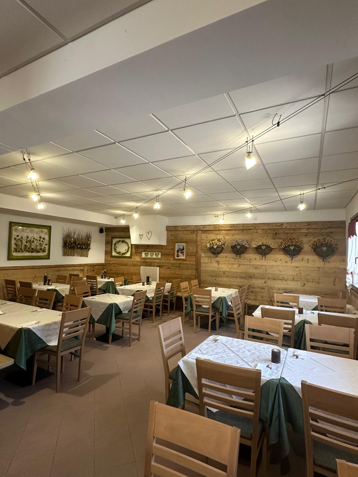 Vista della sala del Ristorante Pizzeria Paradiso, con tavoli apparecchiati e pareti in legno